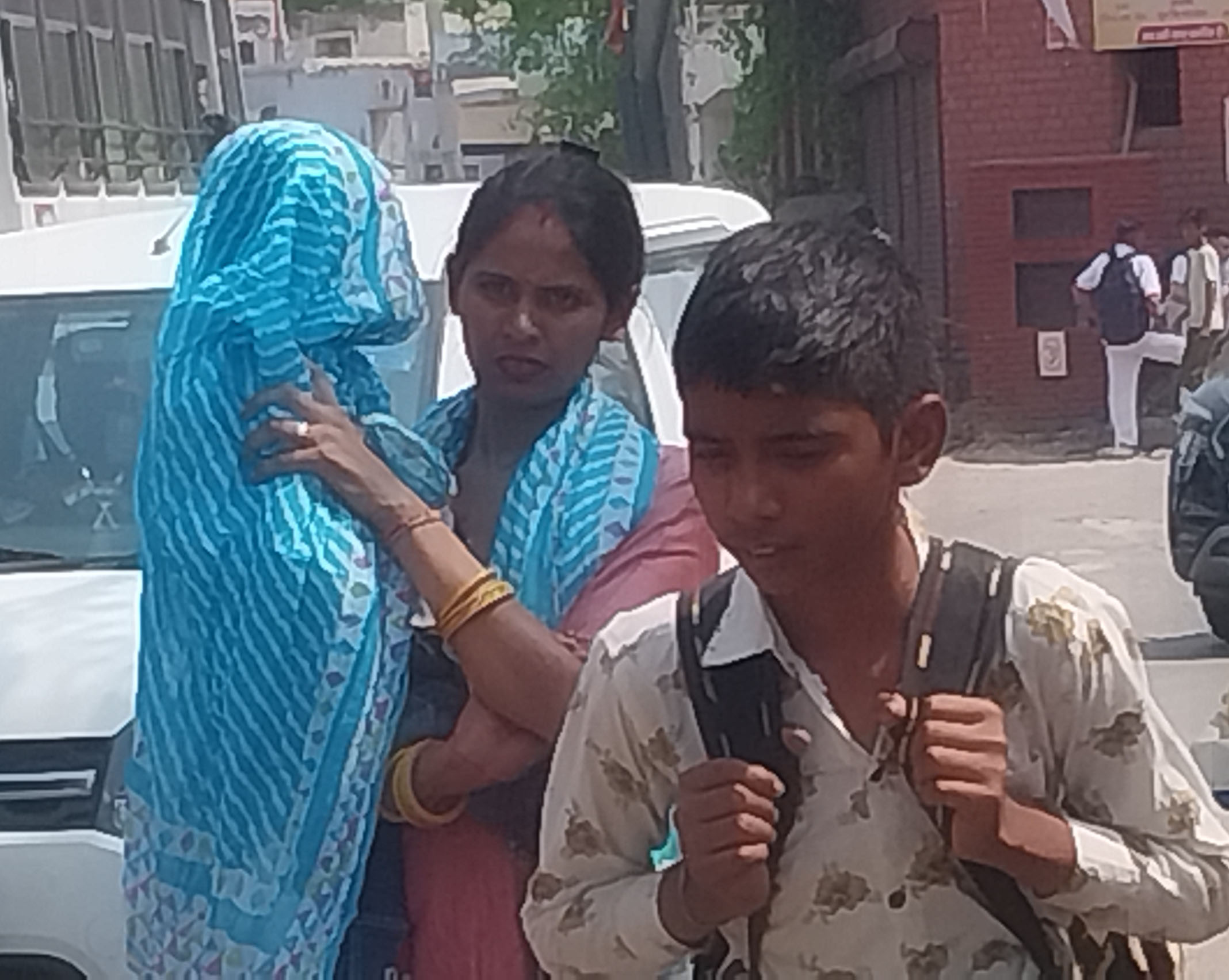 शुक्रवार को तेज धूप से बच्चे का बचाव करती महिला।